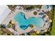 Aerial view of a uniquely shaped community pool area with lounge chairs and umbrellas for relaxation at 5170 Sea Mist Ln, Wesley Chapel, FL 33545