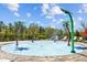 Fun splash pad with palm tree sprayers and lounge chairs, perfect for cooling off on warm days at 5170 Sea Mist Ln, Wesley Chapel, FL 33545