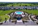 Aerial view of a community pool and recreation center surrounded by well-manicured landscaping and parking at 5470 Flint Hills Dr, Wimauma, FL 33598