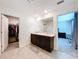 Bathroom featuring double vanity with granite countertops, walk-in closet, and entrance to bedroom at 5470 Flint Hills Dr, Wimauma, FL 33598