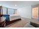 Bedroom with carpet, a large wooden bed and end table, open doorway, and window at 5470 Flint Hills Dr, Wimauma, FL 33598
