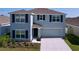 Charming two-story home with gray siding, dark shutters, well-maintained landscaping, and an attached two-car garage at 5470 Flint Hills Dr, Wimauma, FL 33598