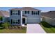Charming two-story home with gray siding, dark shutters, well-maintained landscaping, and an attached two-car garage at 5470 Flint Hills Dr, Wimauma, FL 33598