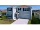 Two-story home with light blue paint, dark shutters, and a well-maintained lawn at 5470 Flint Hills Dr, Wimauma, FL 33598