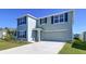 Two-story home boasts gray siding, dark shutters, well-maintained landscaping, and an attached two-car garage at 5470 Flint Hills Dr, Wimauma, FL 33598