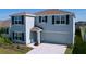 Two-story home boasts gray siding, dark shutters, well-maintained landscaping, and an attached two-car garage at 5470 Flint Hills Dr, Wimauma, FL 33598