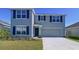 Charming two-story home with gray siding, dark shutters, well-maintained landscaping, and an attached two-car garage at 5470 Flint Hills Dr, Wimauma, FL 33598