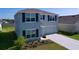 Two-story home boasts gray siding, dark shutters, well-maintained landscaping, and an attached two-car garage at 5470 Flint Hills Dr, Wimauma, FL 33598