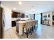 Open-concept kitchen with dark wood cabinets, a center island, and a view into the dining area with a stylish bar cart at 5470 Flint Hills Dr, Wimauma, FL 33598