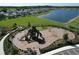 Aerial view of a community playground and green space with a lake in the background at 5470 Flint Hills Dr, Wimauma, FL 33598