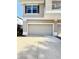 Two-car garage featuring a light-colored door, tan stucco exterior, and well-maintained driveway at 7543 Red Mill Circle Cir, New Port Richey, FL 34653