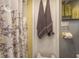 Clean bathroom with yellow tile, decorative shower curtain, and hanging towels at 7901 Marlboro Dr, Port Richey, FL 34668