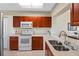 Well-lit kitchen showcasing cherry cabinets, white countertops, and appliances at 7932 Sailboat Key S Blvd # 406, South Pasadena, FL 33707