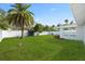 Spacious backyard featuring a large lawn, tall palm tree, storage shed, and white fencing at 8030 Jasmine Blvd, Port Richey, FL 34668