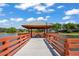 Wooden gazebo with seating area on a pier overlooking a serene lake at 8405 Divot Way, Port Richey, FL 34668