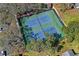 Aerial shot of well-maintained tennis courts surrounded by mature trees, offering a scenic recreational amenity at 8405 Divot Way, Port Richey, FL 34668