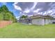 Well-maintained backyard with a screened pool area, lush green lawn, and mature palm trees at 9813 Woodbay Dr, Tampa, FL 33626