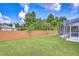 Lush backyard featuring a wood fence, green lawn, and a screened-in pool area for outdoor enjoyment at 9813 Woodbay Dr, Tampa, FL 33626