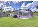 Backyard view showcasing a beautiful screened-in pool and spa area in lush green lawn at 9813 Woodbay Dr, Tampa, FL 33626