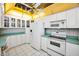 Bright kitchen with white cabinets, appliances, and tile flooring, complemented by unique yellow accents and a ceiling fan at 100 Bluff View Dr # 511C, Belleair Bluffs, FL 33770