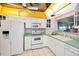 Kitchen featuring white appliances, cabinets, and tile floor, under a unique gold framed ceiling panel at 100 Bluff View Dr # 511C, Belleair Bluffs, FL 33770