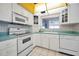 Kitchen featuring white cabinets, range and microwave, and tile floors, with a view from the window at 100 Bluff View Dr # 511C, Belleair Bluffs, FL 33770