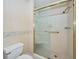 Glass enclosed shower with gold trim in a bathroom with tiled walls and floors and a comfort height toilet at 100 Bluff View Dr # 511C, Belleair Bluffs, FL 33770