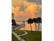 Stunning waterfront views with vibrant sunset hues from the condo's lawn with tropical trees at 100 Bluff View Dr # 511C, Belleair Bluffs, FL 33770
