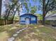 Beautiful blue home surrounded by mature trees, showcasing a welcoming front porch and a stone pathway at 1019 E Mohawk Ave, Tampa, FL 33604