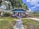 Charming blue home featuring a cozy front porch with classic brick accents and a convenient covered parking area at 1019 E Mohawk Ave, Tampa, FL 33604