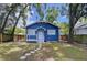 Inviting blue craftsman-style home with a covered porch, framed by lush trees and a well-manicured lawn at 1019 E Mohawk Ave, Tampa, FL 33604