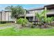 Condo exterior featuring lush tropical landscaping, a well-maintained lawn, and exterior stairs leading to a second-story entrance at 10265 Gandy N Blvd # 1702, St Petersburg, FL 33702