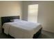 Simple bedroom featuring a bed with a dark headboard, white bedding, and a window for natural light at 11513 Andy Dr, Riverview, FL 33569
