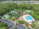 Aerial view of community pool, clubhouse, tennis courts, parking, and surrounding landscape at 1342 Salmonberry St, Wesley Chapel, FL 33543