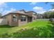 The backyard has a well-maintained lawn and a neutral-colored exterior with a screened in patio at 1342 Salmonberry St, Wesley Chapel, FL 33543