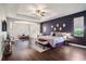 Large main bedroom features dark accent wall, tray ceiling, sitting area and hardwood floors at 1342 Salmonberry St, Wesley Chapel, FL 33543