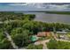 Breathtaking aerial view of a home with a pool near a lake surrounded by verdant trees at 1401 Camelot Ct, Palm Harbor, FL 34684