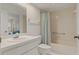 Bathroom featuring vanity, toilet, tub and shower combination with neutral tile and striped curtain at 1401 Camelot Ct, Palm Harbor, FL 34684