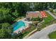 Overhead view showcasing a community pool with lounge chairs, umbrellas, and outdoor dining area at 1401 Camelot Ct, Palm Harbor, FL 34684