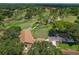 Scenic aerial shot of the golf course and clubhouse bordered by mature trees at 1401 Camelot Ct, Palm Harbor, FL 34684