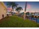 Green lawn leading to the waterfront, featuring a pool and lit patio for nighttime ambiance at 1424 47Th Ne Ave, St Petersburg, FL 33703