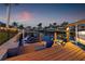 Inviting waterfront space featuring comfortable seating, wooden dock, boat lift, and scenic views of the waterway at dusk at 1424 47Th Ne Ave, St Petersburg, FL 33703