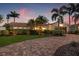 Beautifully landscaped single-story home with a paver driveway, mature palms and lush landscaping under an colorful evening sky at 1424 47Th Ne Ave, St Petersburg, FL 33703