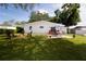 Landscaped backyard with a fire pit, patio with an umbrella table set, and green lawn at 2010 6Th Sw Ave, Largo, FL 33770