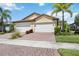 Spacious home featuring a well-maintained front yard, brick driveway, and a two-car garage at 21008 Fetterbush Pl, Venice, FL 34293