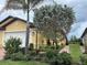 Charming yellow home featuring lush landscaping, brick walkway, and mature palm trees for a tropical feel at 21008 Fetterbush Pl, Venice, FL 34293