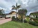 Attractive yellow home with a two-car garage, brick driveway, and a beautifully landscaped front yard at 21008 Fetterbush Pl, Venice, FL 34293