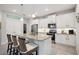 Modern kitchen featuring an island with bar seating, white cabinets, and stainless steel appliances at 21008 Fetterbush Pl, Venice, FL 34293