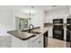 Modern kitchen featuring stainless steel appliances, granite countertops, and a breakfast bar with a view to a sliding glass door at 2171 Portofino Pl # 27-2725, Palm Harbor, FL 34683