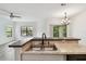 Kitchen island featuring stainless steel sink and granite countertop with breakfast bar looking out towards a sunny living room and sliding glass doors at 2171 Portofino Pl # 27-2725, Palm Harbor, FL 34683